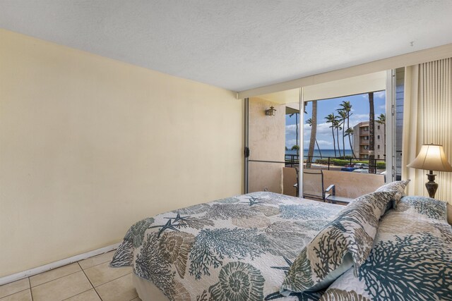 tiled bedroom featuring a textured ceiling and a water view