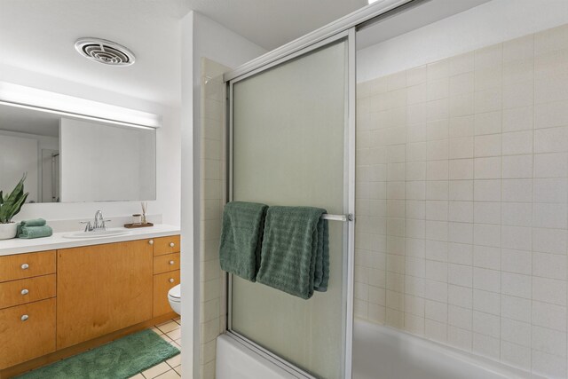 full bathroom with combined bath / shower with glass door, toilet, tile patterned flooring, and vanity