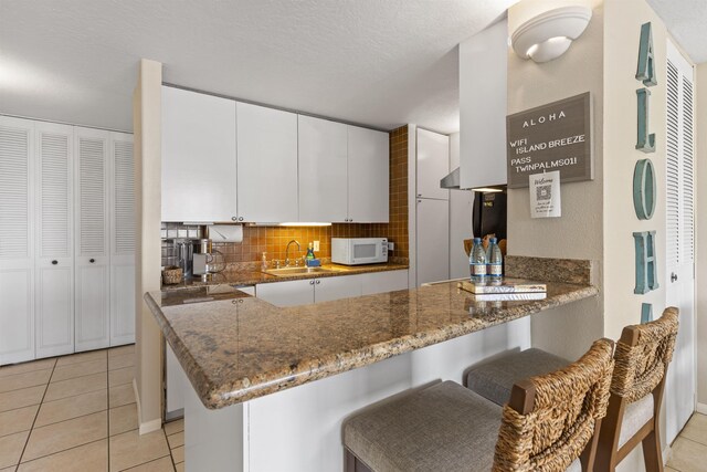 kitchen with decorative backsplash, kitchen peninsula, and a kitchen bar