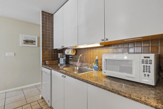 kitchen featuring decorative backsplash, sink, white cabinets, light tile patterned floors, and white appliances