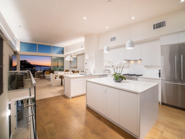 kitchen with white cabinetry, backsplash, pendant lighting, a kitchen island, and appliances with stainless steel finishes