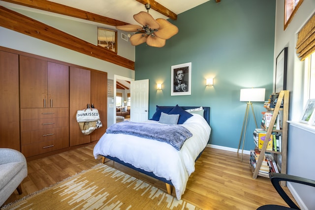 bedroom featuring light hardwood / wood-style floors, beamed ceiling, a high ceiling, and ceiling fan