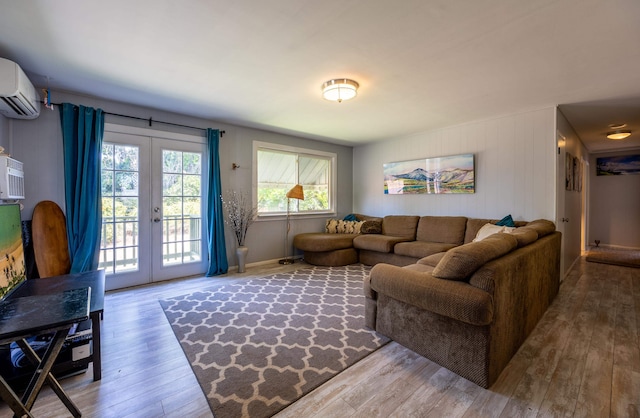 living room featuring a wall mounted air conditioner, french doors, and hardwood / wood-style floors