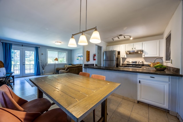 kitchen with appliances with stainless steel finishes, french doors, white cabinetry, and pendant lighting