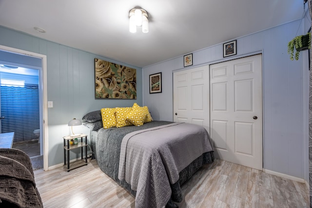 bedroom with a closet, light wood-type flooring, and wood walls