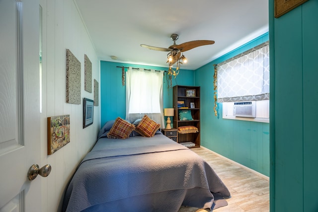 bedroom with cooling unit, multiple windows, light wood-type flooring, and ceiling fan