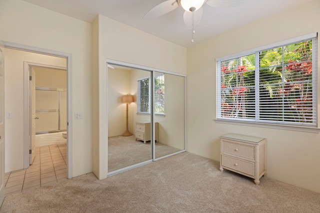 unfurnished bedroom featuring light carpet, a closet, and ceiling fan