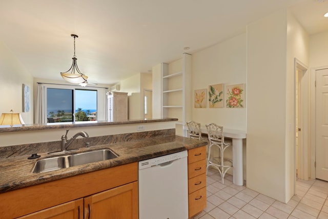 kitchen with dishwasher, sink, pendant lighting, dark stone counters, and light tile patterned flooring