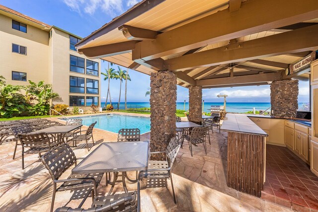 view of swimming pool featuring ceiling fan, a patio, and a water view