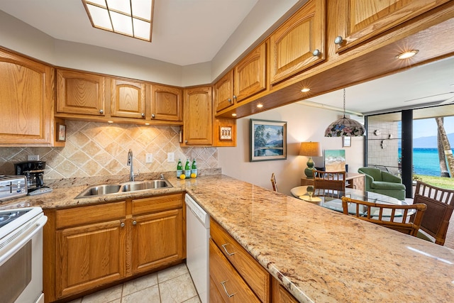 kitchen with a water view, light stone countertops, light tile patterned floors, white appliances, and sink