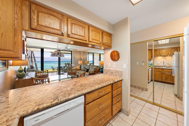 kitchen featuring tasteful backsplash, ceiling fan, a water view, light tile patterned floors, and white appliances