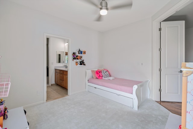 bedroom with connected bathroom, light colored carpet, sink, and ceiling fan