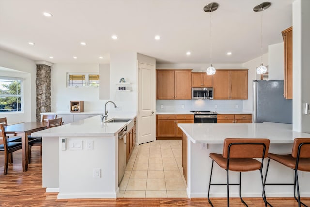 kitchen featuring sink, tasteful backsplash, decorative light fixtures, light tile patterned floors, and stainless steel appliances