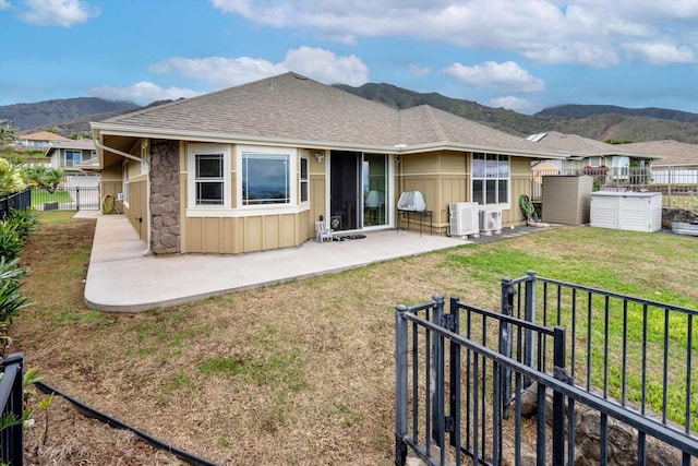 rear view of property featuring a mountain view, a yard, and a patio area