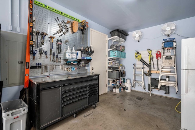 garage with a workshop area, electric panel, and white refrigerator