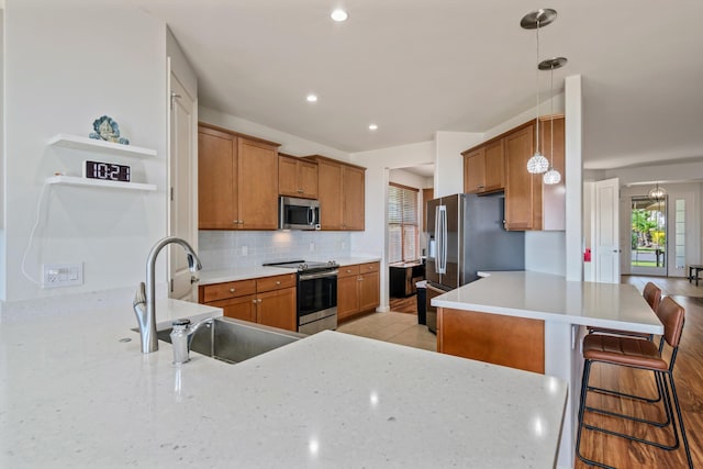 kitchen featuring pendant lighting, sink, a breakfast bar, stainless steel appliances, and tasteful backsplash