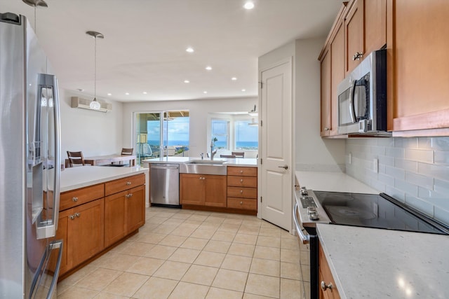 kitchen with sink, a wall mounted AC, hanging light fixtures, appliances with stainless steel finishes, and decorative backsplash