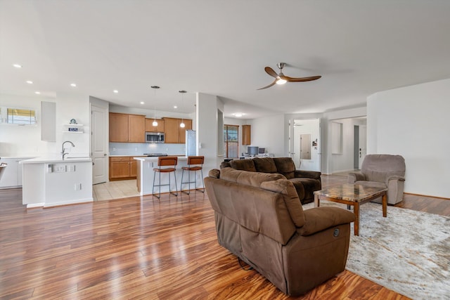 living room with sink, light hardwood / wood-style floors, and ceiling fan