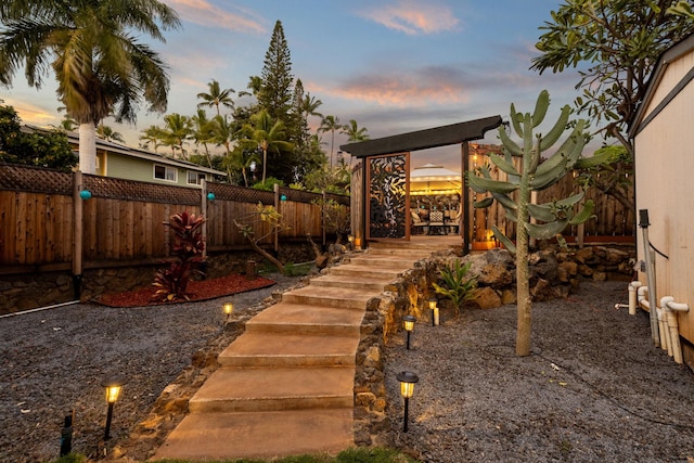 yard at dusk featuring a fenced backyard