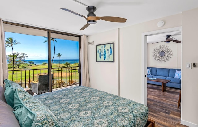 bedroom with hardwood / wood-style floors, access to outside, a water view, ceiling fan, and a wall of windows