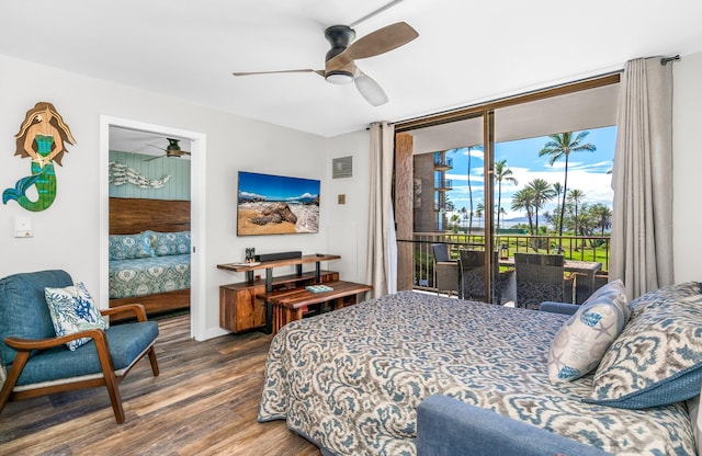 bedroom featuring access to outside, ceiling fan, wood-type flooring, and a wall of windows