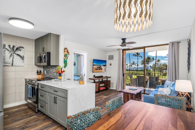 kitchen with backsplash, ceiling fan, gray cabinets, dark hardwood / wood-style flooring, and stainless steel appliances