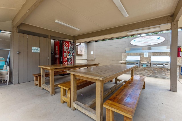 dining area with a workshop area, concrete floors, and concrete block wall