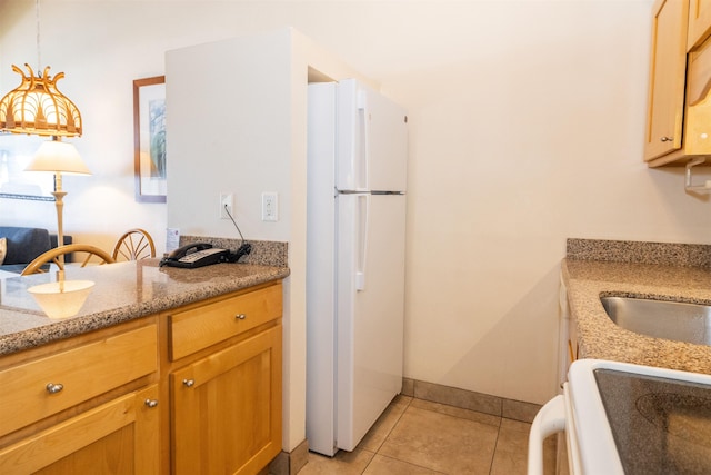 kitchen with light stone countertops, white refrigerator, pendant lighting, light tile patterned floors, and range