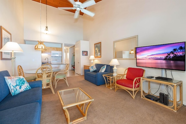 carpeted living room with ceiling fan, sink, and a high ceiling