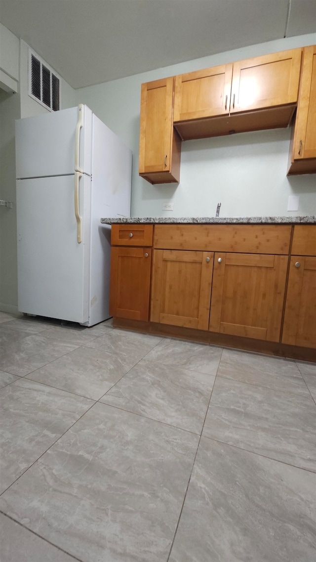 kitchen with light stone countertops and white refrigerator