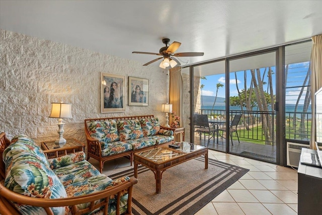 tiled living room with ceiling fan, a water view, and expansive windows