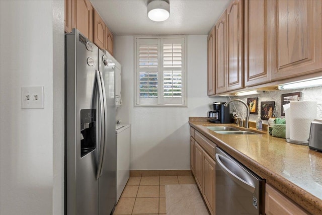 kitchen with stainless steel appliances, sink, light stone counters, light tile patterned floors, and decorative backsplash