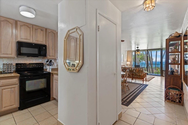 kitchen with light tile patterned floors, light brown cabinetry, black appliances, and floor to ceiling windows