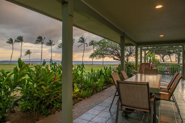 patio terrace at dusk with a water view and outdoor dining area