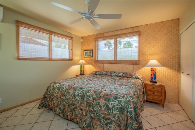 bedroom with light tile patterned floors, an accent wall, an AC wall unit, and ceiling fan