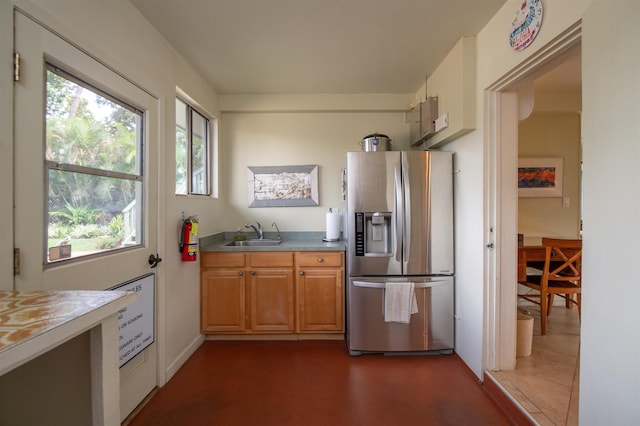 kitchen with brown cabinets, stainless steel fridge, a sink, and light countertops