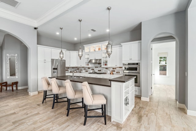 kitchen with white cabinetry, decorative backsplash, stainless steel appliances, and an island with sink