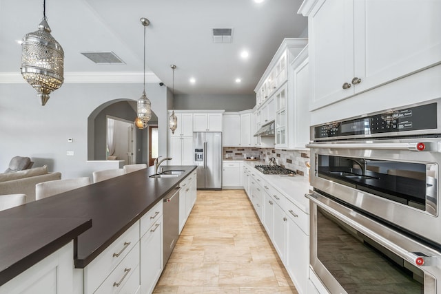 kitchen with appliances with stainless steel finishes, decorative light fixtures, sink, white cabinets, and decorative backsplash