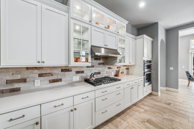 kitchen with white cabinetry, stainless steel appliances, light hardwood / wood-style floors, and tasteful backsplash