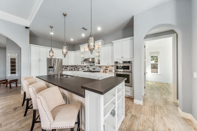 kitchen featuring sink, pendant lighting, stainless steel appliances, a kitchen island with sink, and white cabinets