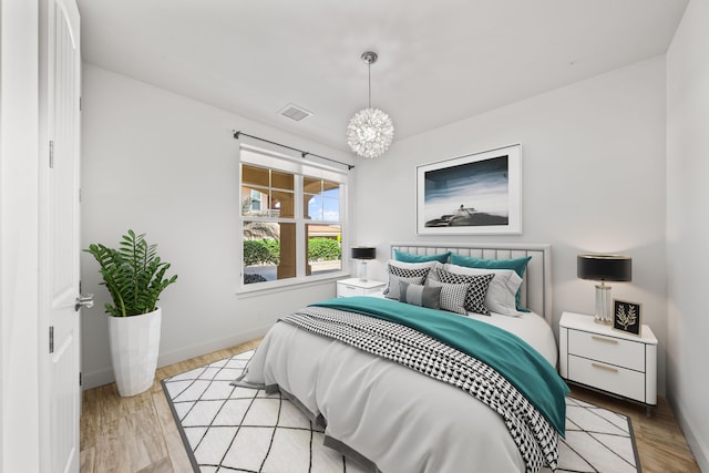 bedroom featuring light hardwood / wood-style flooring and a chandelier