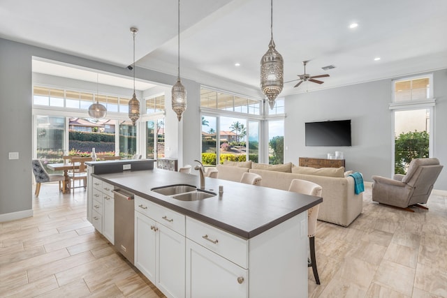 kitchen with sink, white cabinetry, a center island with sink, stainless steel dishwasher, and pendant lighting