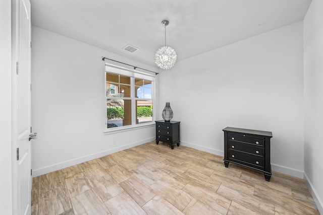 spare room with an inviting chandelier and light wood-type flooring