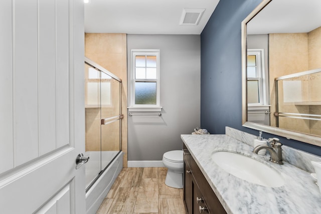 full bathroom featuring vanity, enclosed tub / shower combo, and toilet