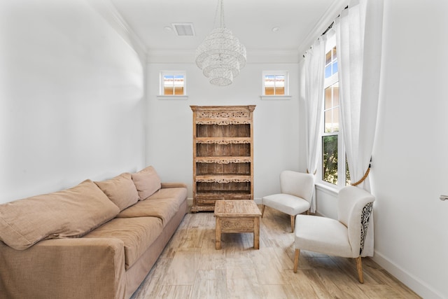 living room featuring ornamental molding, a chandelier, and light hardwood / wood-style flooring