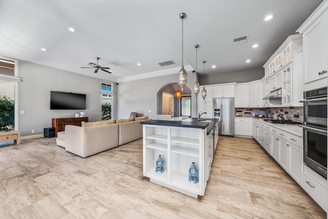 kitchen with appliances with stainless steel finishes, pendant lighting, sink, white cabinets, and a kitchen island with sink