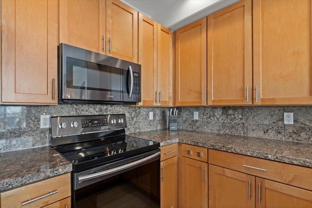 kitchen with decorative backsplash, dark stone counters, and appliances with stainless steel finishes