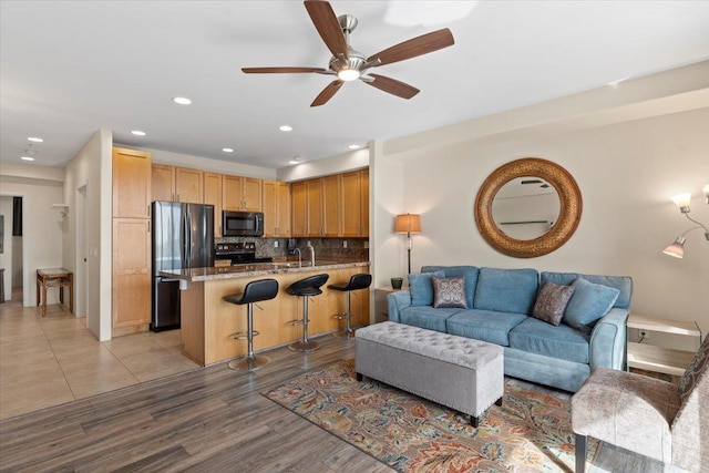 living room featuring ceiling fan, light wood-type flooring, and sink