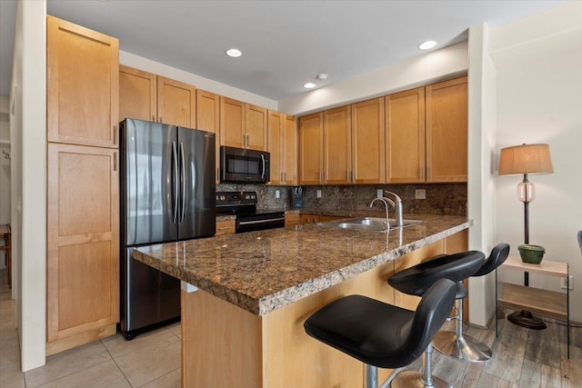 kitchen with a kitchen breakfast bar, sink, stainless steel fridge, black range with electric cooktop, and kitchen peninsula