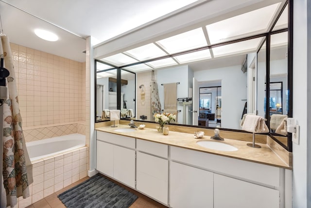 full bath featuring tiled shower / bath, double vanity, a sink, and ensuite bathroom